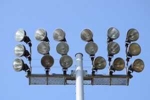 Industrial outdoor lights against a blue sky.